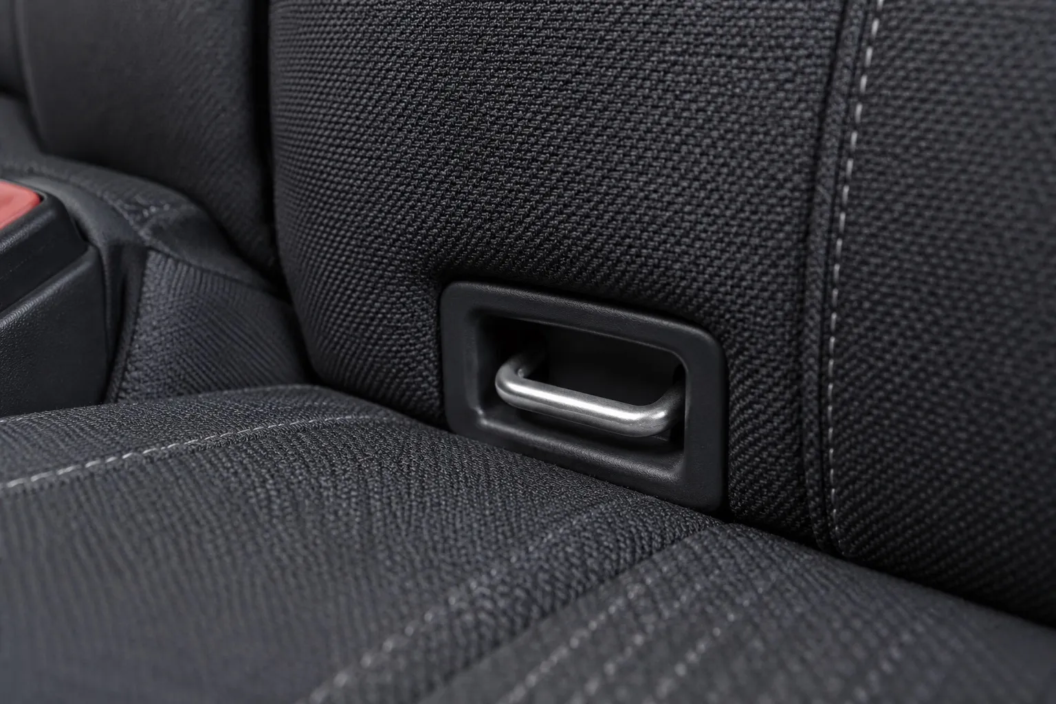 Крупный план штатной металлической скобы ISOFIX между подушкой и спинкой заднего сиденья, без установленного детского кресла