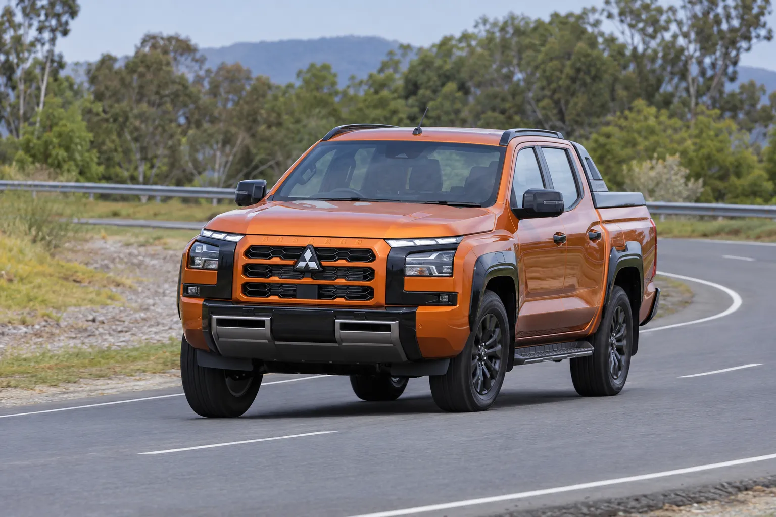 Mitsubishi Triton VI на плавном повороте дороги